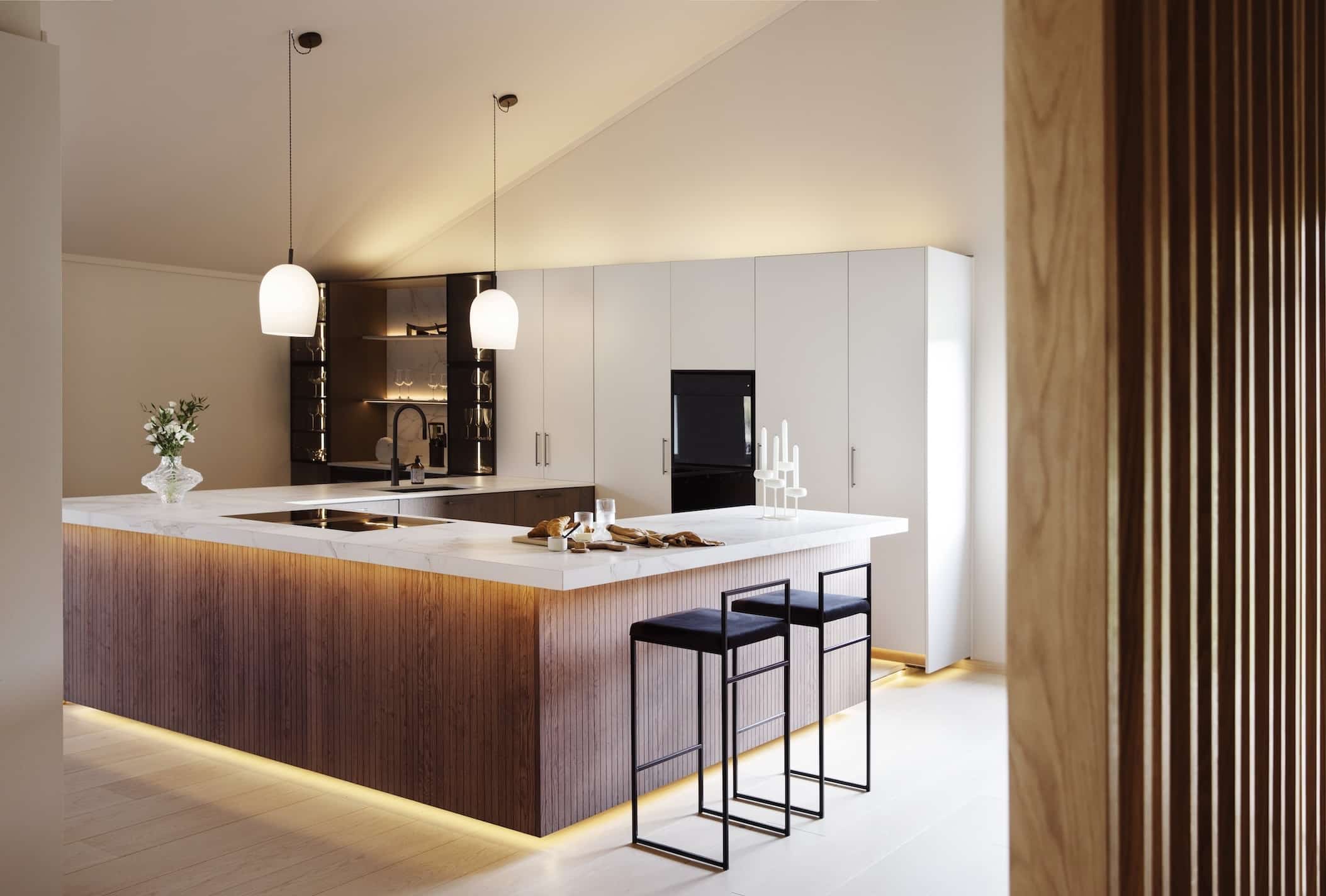 Plan de travail en forme de U en granit dekton entzo avec une plaque de cuisson et un évier dans une cuisine claire et minimaliste