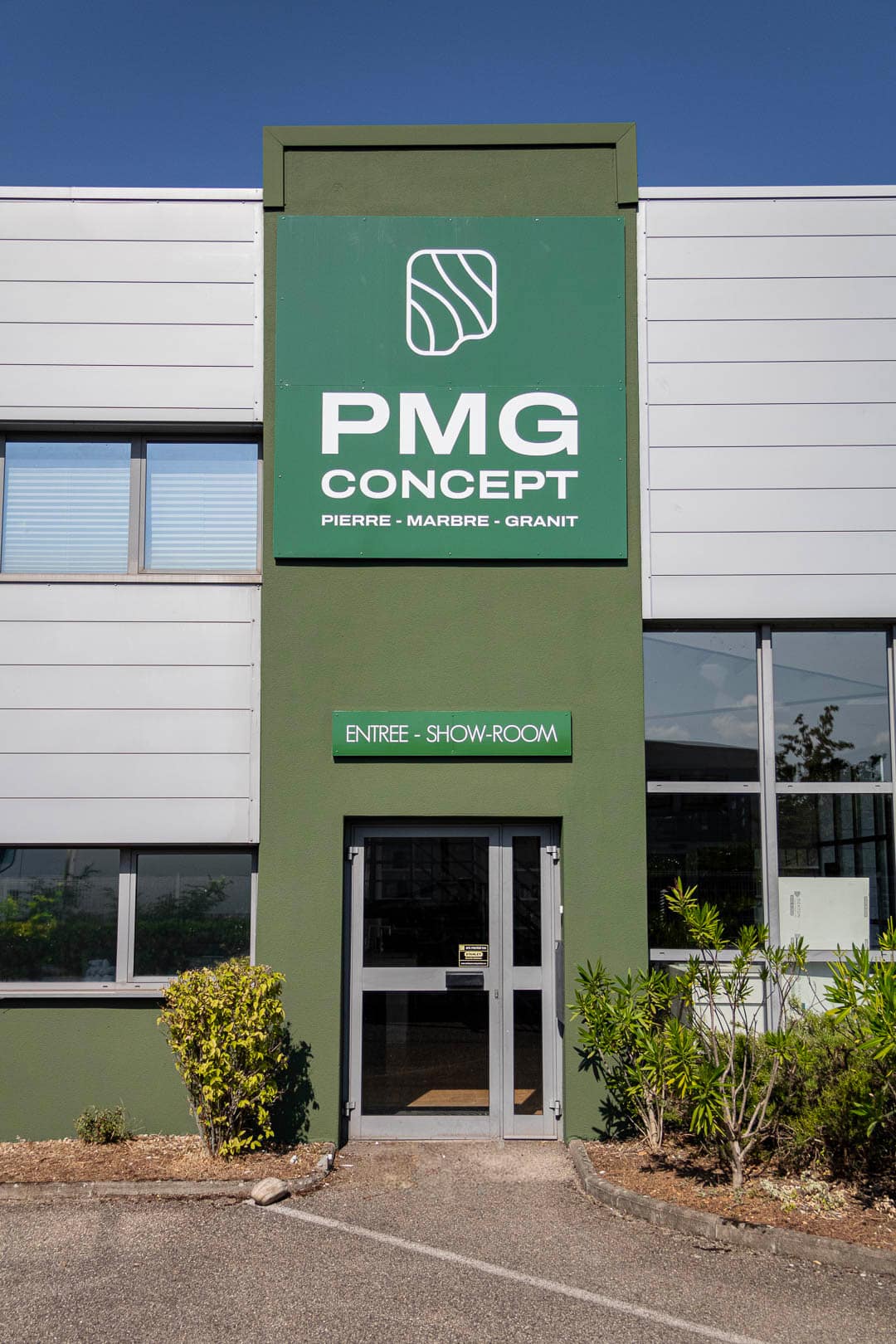 Devanture verte des locaux de l'entreprise d'artisans marbriers PMG Concept avec le logo de l'entreprise