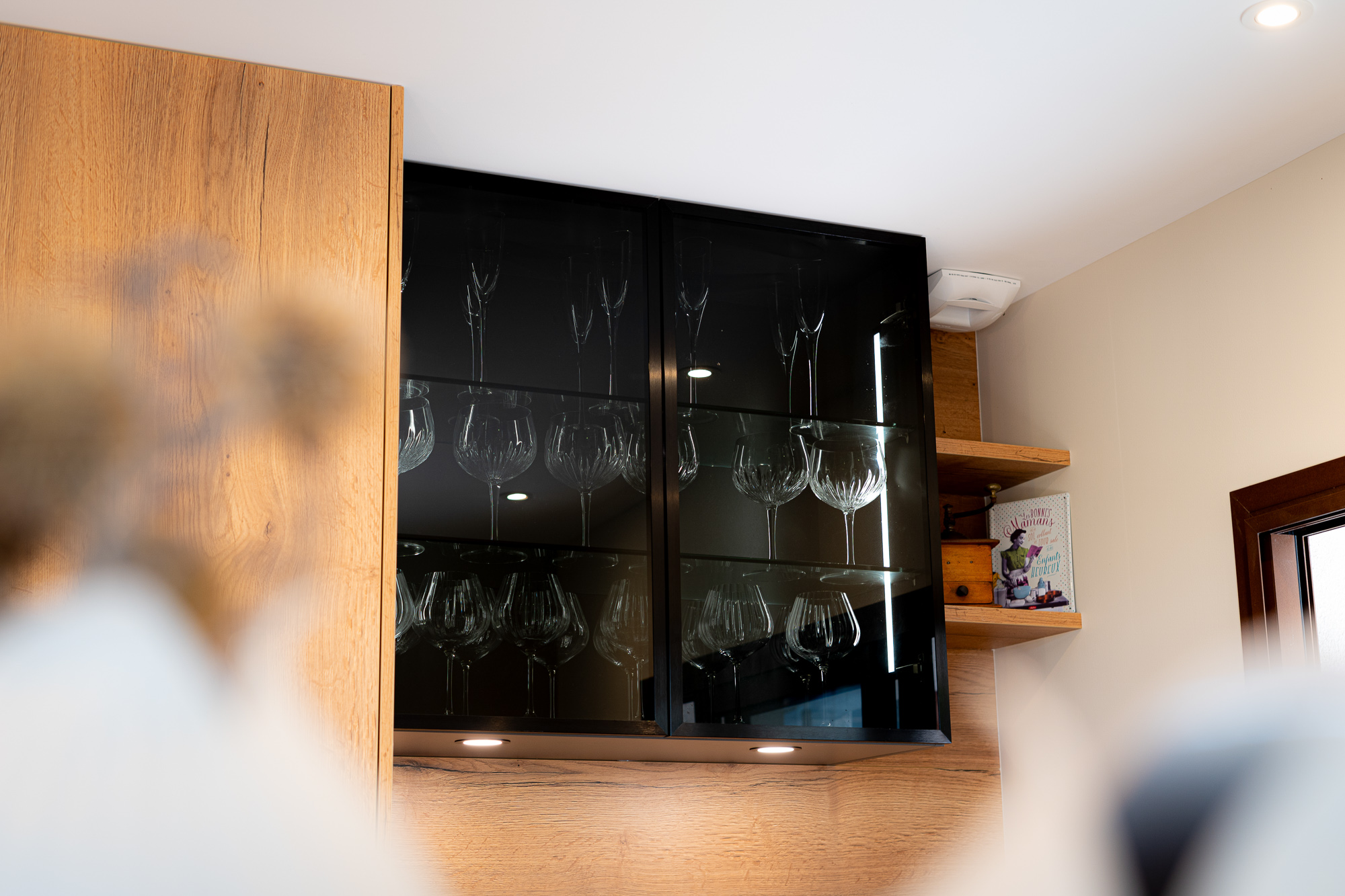 Meuble à verres noir dans une cuisine moderne boisée