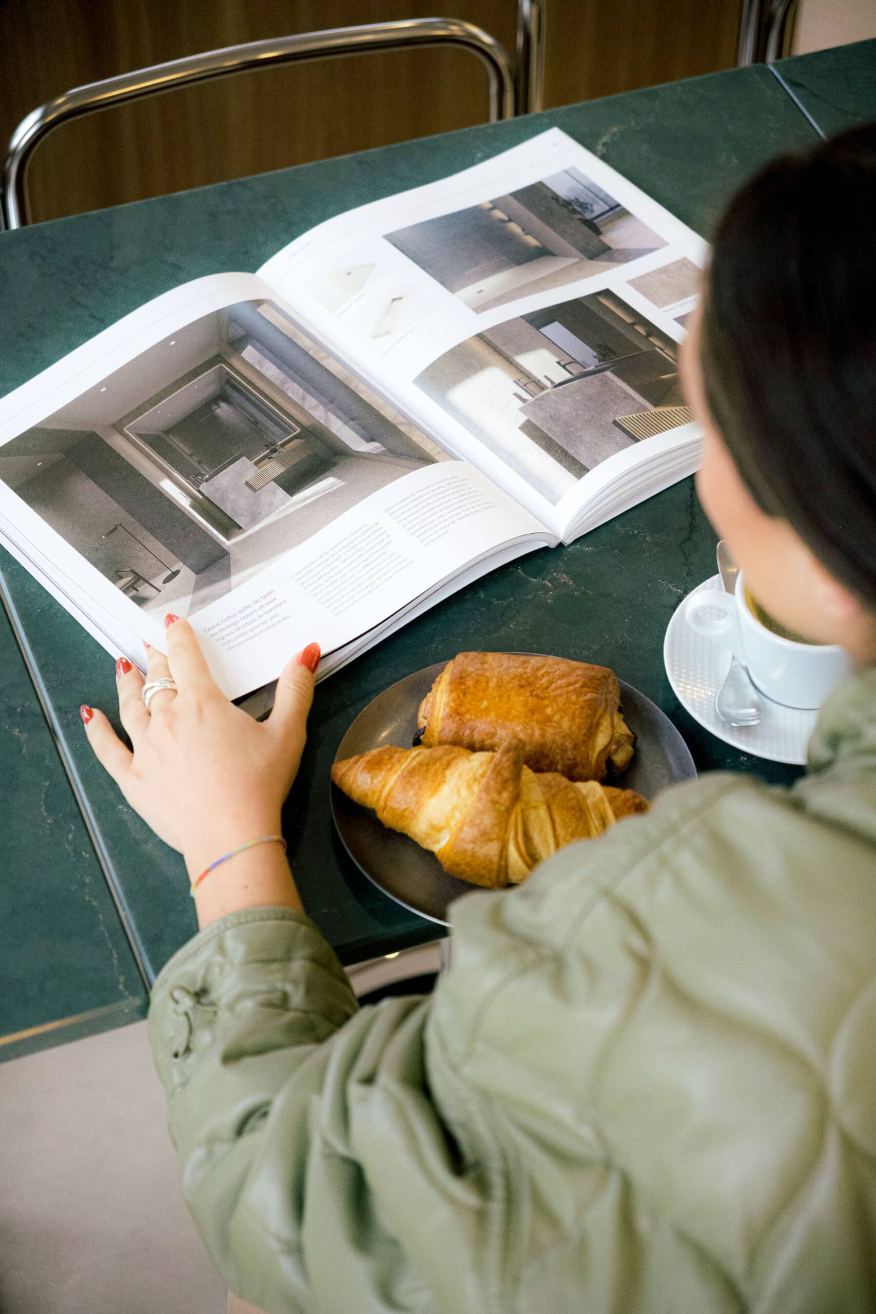Personne buvant un café et mangeant un croissant en lisant un magazine sur une table dans un bar à Lyon