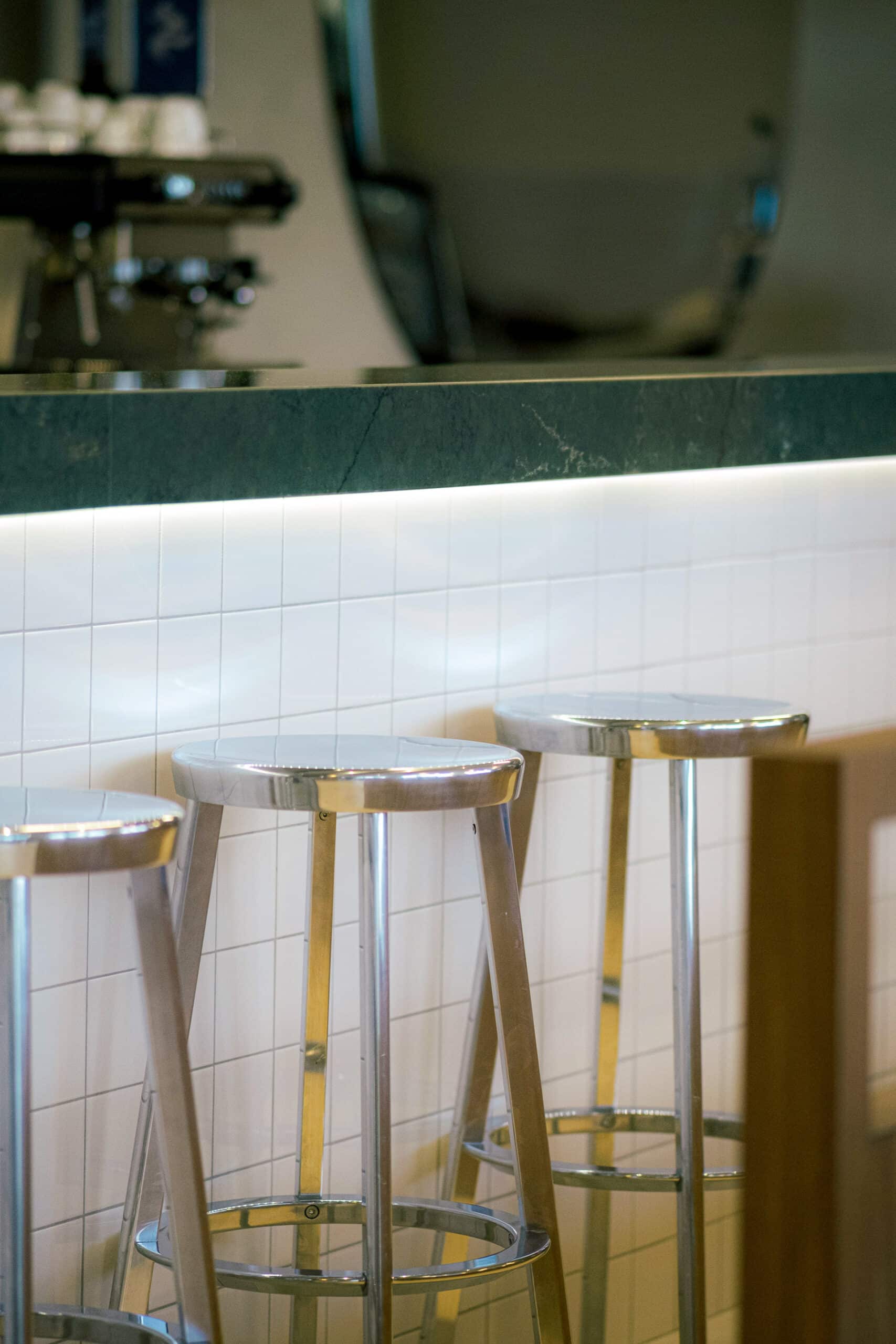 Tabouret en métal devant un bar sur mesure en silestone Jardin Emerald