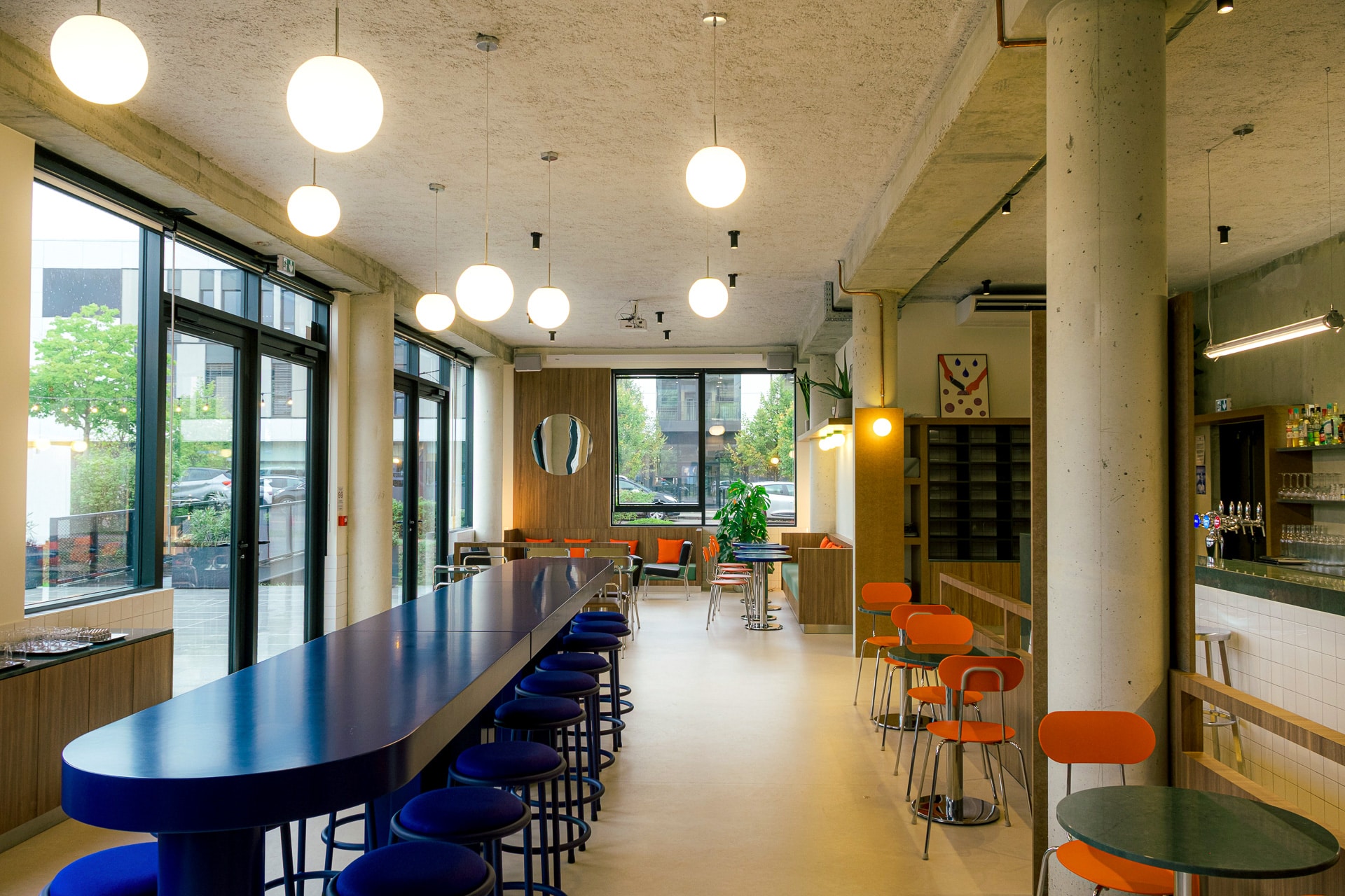 Vue d'ensemble sur un bar situé à Limonest à 2 pas de Lyon avec une longue table haute bleue, des tables sur mesure et un bar en silestone jardin emerald