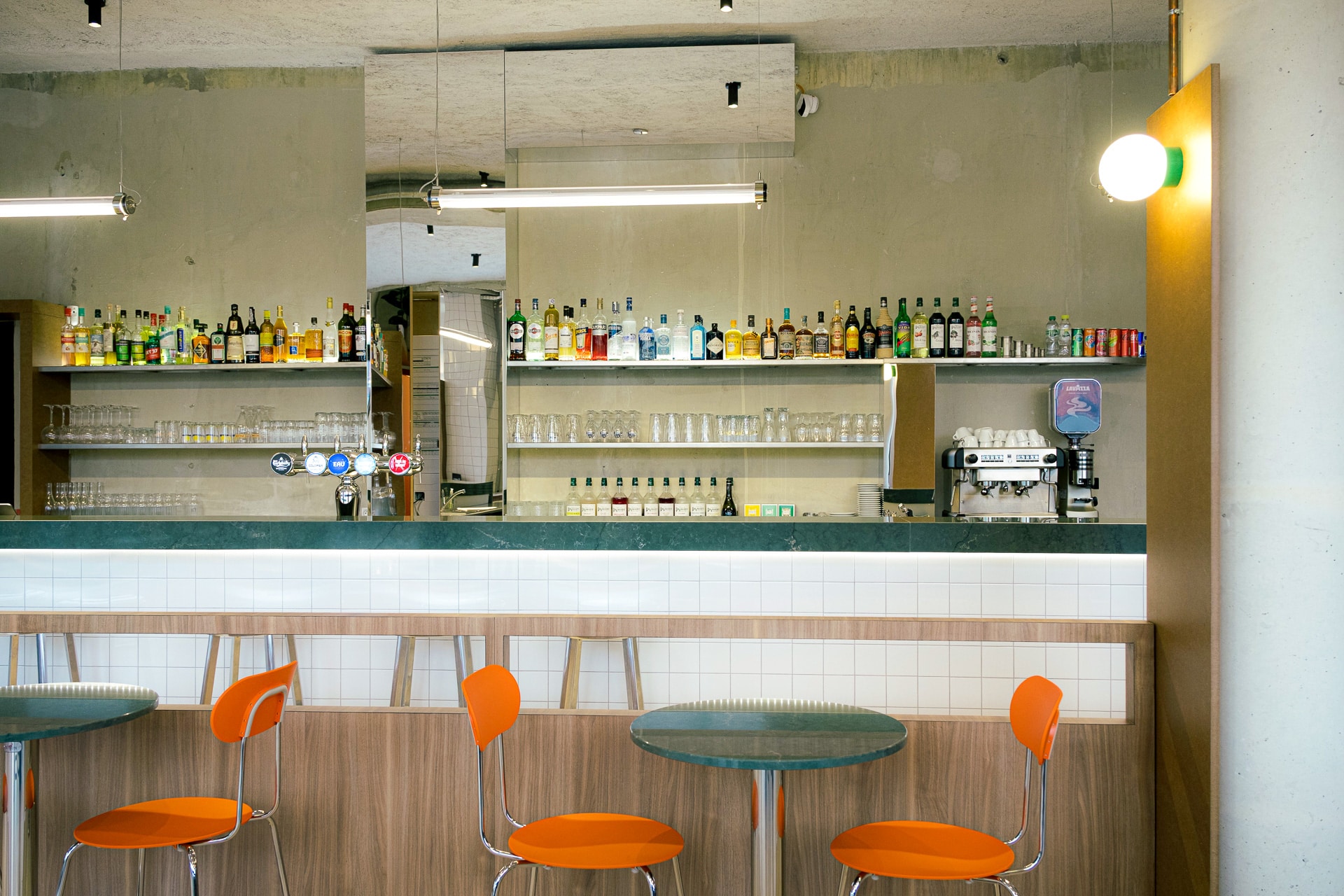 Bar vert avec des chaises orange et des tables sur mesure
